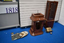 A selection of long case clock parts including figured mahogany case, faces , pendulums and