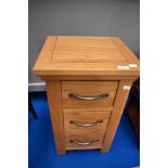 A modern golden oak three drawer bedside chest