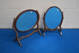 Two Edwardian mahogany swing mirrors, each of oval form and pivoted between curved supports and