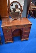 A Queen Anne style kneehole desk having nine drawers, fitted with later mirror to form a dressing