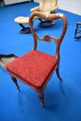 A Victorian balloon back chair with carved legs and back.