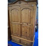 A modern natural pine wardrobe having double drawers to base