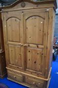 A modern natural pine wardrobe having double drawers to base