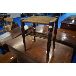 A traditional stained frame stool with strung seat