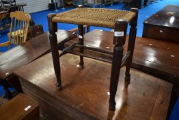 A traditional stained frame stool with strung seat