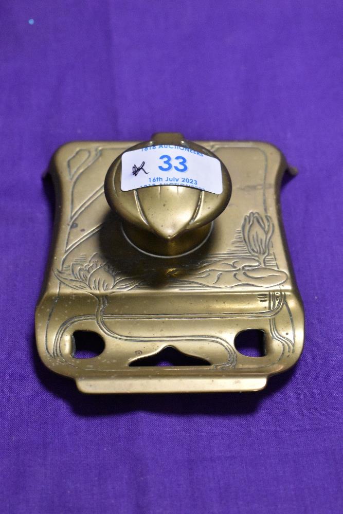 A small brass inkwell pen rest