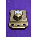 A small brass inkwell pen rest