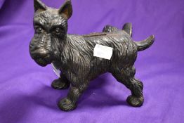 A vintage cast metal money bank, modelled as cock legged dog.