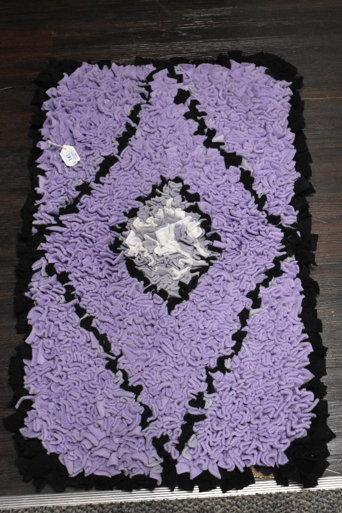 An as new, handmade peggy/ proddy rug in purple, black and white.