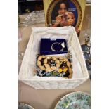 A basket of mixed costume jewellery, to include an amber coloured necklace, bangles, and other