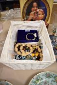 A basket of mixed costume jewellery, to include an amber coloured necklace, bangles, and other