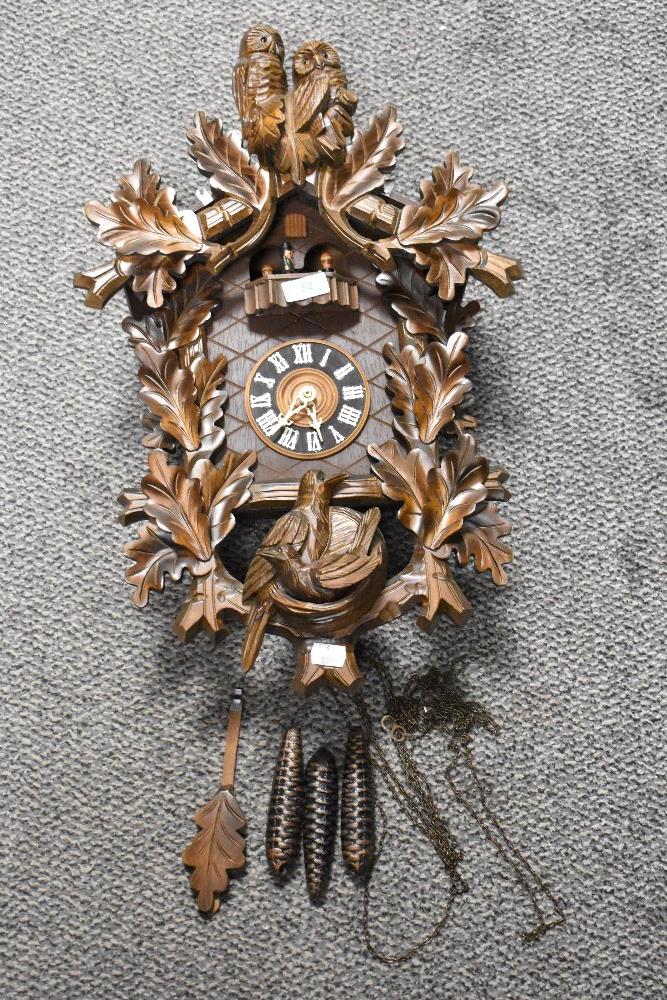 A traditional cuckoo style clock having additional owl decoration and revolving mechanism