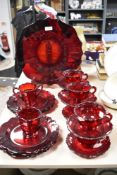 A collection of mid century ruby glass cups and saucers, plates and sugar basin.