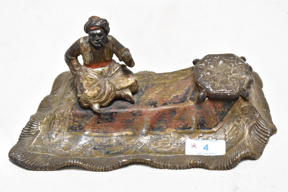 After bergmann, a cold painted cast metal ink well depicting smoking man on flying carpet