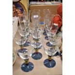 Eight wine glasses and nine champagne flutes, having colourful knopped stems, aloft blue lustre