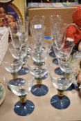 Eight wine glasses and nine champagne flutes, having colourful knopped stems, aloft blue lustre