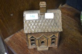 A vintage cast metal piggy bank modelled as a cottage
