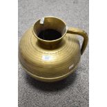 A 20th century large brass jug/ receptacle with handle, having embossed detailing.