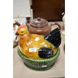 An egg holder in the form of a hen and a large vintage brown enamel teapot.