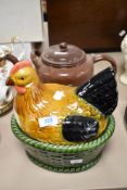 An egg holder in the form of a hen and a large vintage brown enamel teapot.