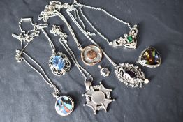 A selection of silver and white metal pendants, several stamped silver including butterfly wing,