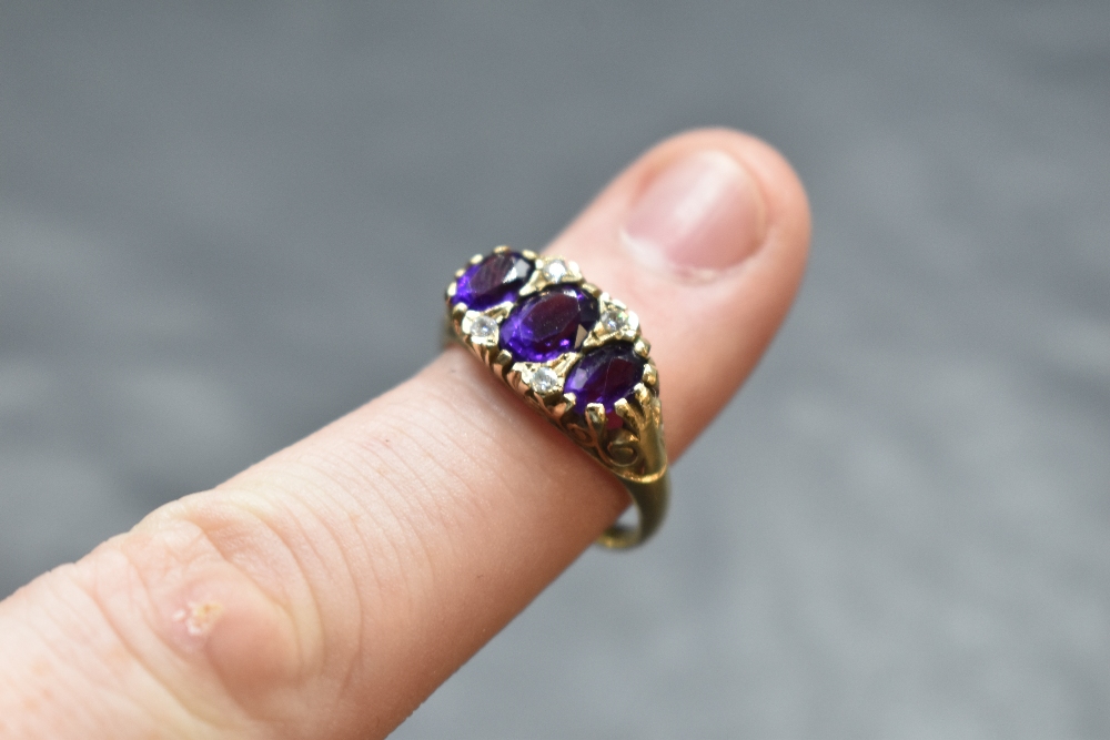 An amethyst trio ring having cubic zirconia spacers in a scrolled gallery mount and 9ct gold loop, - Image 2 of 2