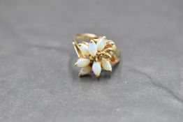 An opal and diamond chip ring having seven opal cabochons modelled as a stylised flower to claw