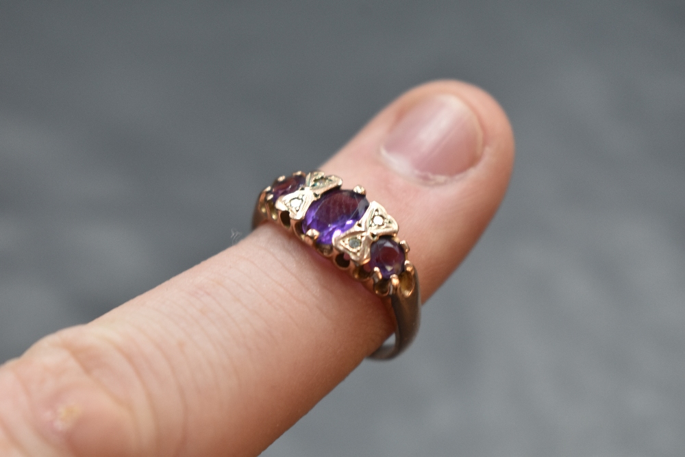 A three stone amethyst ring having diamond chip spacers in a gallery mount on a 9ct rose gold - Image 2 of 2