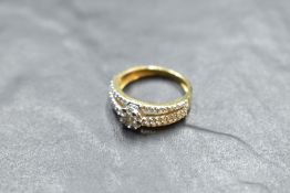 A yellow metal diamond set ring, the central flower head arrangement of brilliant cut diamonds
