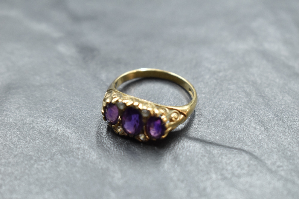 An amethyst trio ring having cubic zirconia spacers in a scrolled gallery mount and 9ct gold loop,