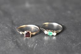 A small emerald and diamond trilogy ring having central baguette cut emerald on a thin white metal