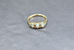 An opal and diamond ring having a trio of opal cabochons with diamond chip spacers in a gallery