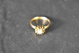 A diamond solitaire ring, approx 0.125ct in a 4 claw set stylised star burst mount on an 18ct gold
