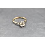 A solitaire ring bearing a clear stone, not a diamond in a raised claw set mount on a yellow metal
