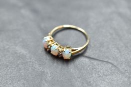 A 9ct gold opal and cubic zirconium ring, the oval opal cabochons interspersed by small brilliant-