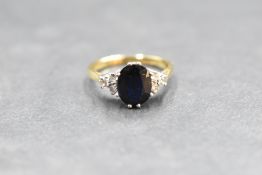 A sapphire ring having a central facet cut oval stone having a trio of small diamonds to each side