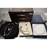 A modern three-drawer jewellery case containing a variety of white metal and costume earrings,