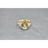 An oval yellow sapphire ring flanked by two small diamonds on a 9ct gold loop, size O & approx 2.5g