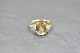 An oval yellow sapphire ring flanked by two small diamonds on a 9ct gold loop, size O & approx 2.5g
