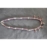 A rough cut amethyst necklace having collared garnet drops and white metal bead spacers, approx 16'