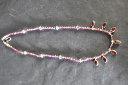 A rough cut amethyst necklace having collared garnet drops and white metal bead spacers, approx 16'