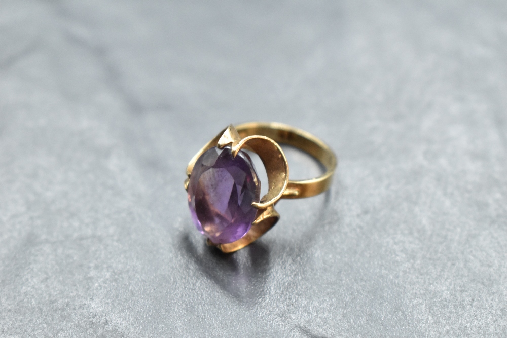 An oval amethyst ring having a claw set stylised mount on a 9ct gold loop, size M & approx 4.7g