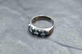 A three stone square cut blue topaz ring having bar settings on a white metal loop stamped C0-074,