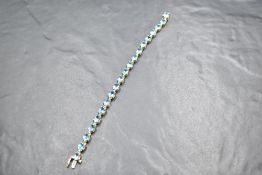 A yellow metal bracelet stamped 14K having twenty blue topaz stones and a concealed clasp, approx