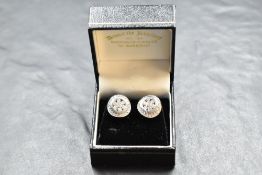 A pair of white metal and diamond earrings, of circular form with an arrangement of diamond