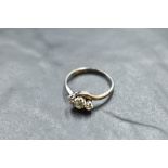 A diamond trilogy ring, total approx 0.35ct having cross over shoulders on a white metal loop