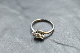 A diamond trilogy ring, total approx 0.35ct having cross over shoulders on a white metal loop