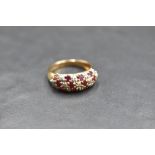 A ruby and diamond chip triple row band ring having moulded shoulders to a 9ct gold loop, size O &