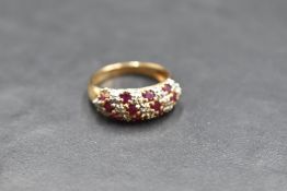 A ruby and diamond chip triple row band ring having moulded shoulders to a 9ct gold loop, size O &