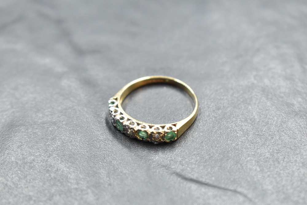 An emerald and diamond half eternity ring having an illusionary setting on a 9ct gold loop, size R &